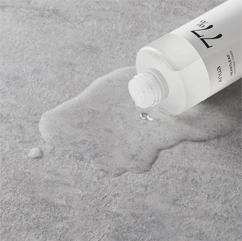Anua Heartleaf 77% Soothing Toner bottle lying on its side with toner spilled on a textured surface.