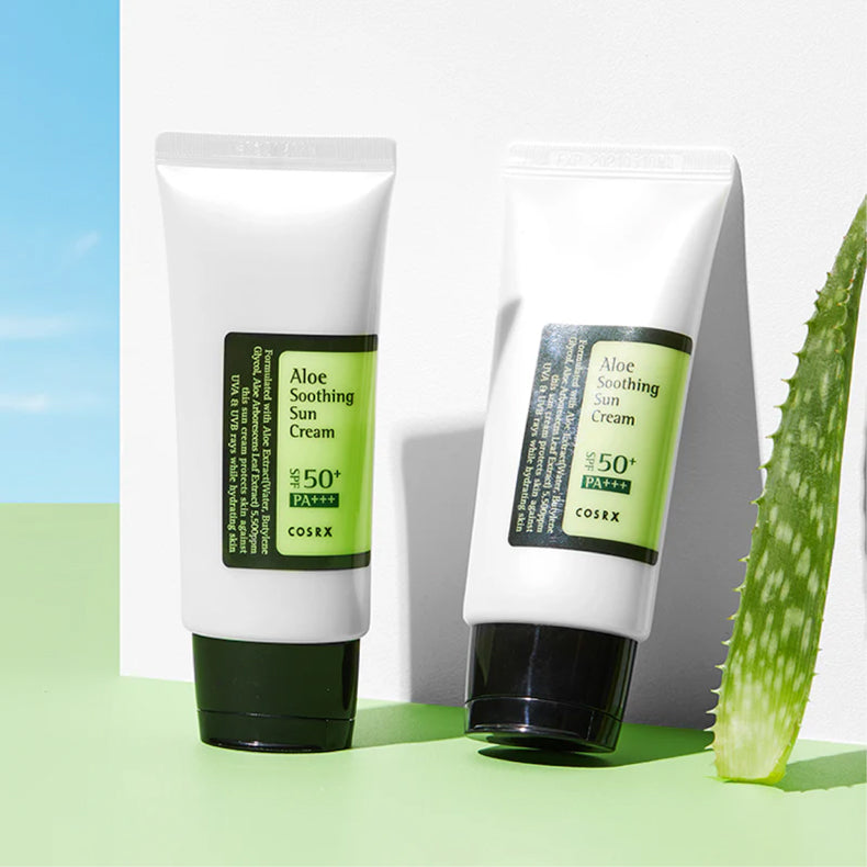 Twee tubes COSRX Aloe Soothing Sun Cream SPF 50+ PA+++ tegen een heldere achtergrond, met een aloë vera blad ernaast.