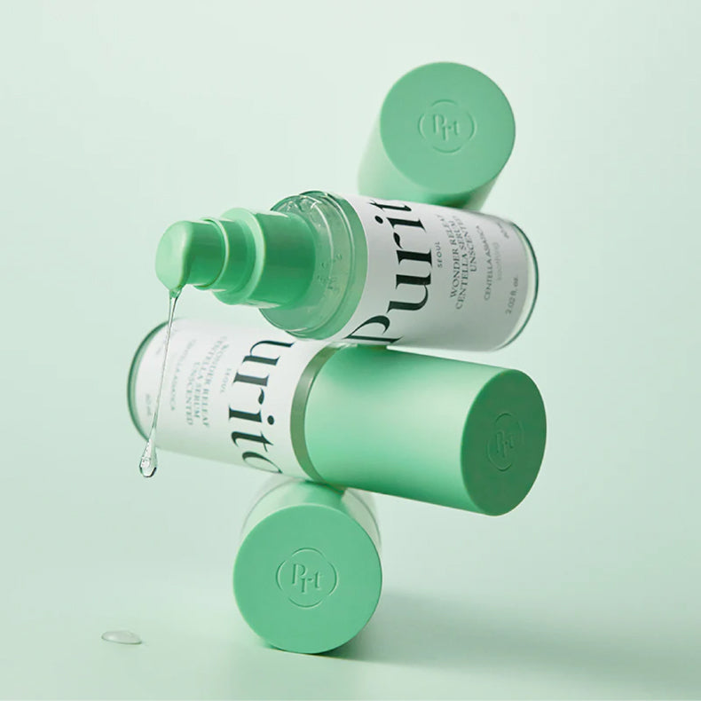 Several bottles of Purito Wonder Relief Centella Serum Unscented, arranged creatively with one bottle dispensing a droplet of serum, all against a mint green background.