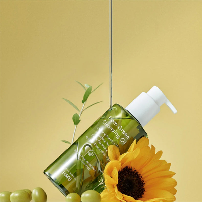 Purito From Green Cleansing Oil bottle positioned on a yellow background with a fresh sunflower, green olives, and an olive branch, with a clear oil stream pouring from above