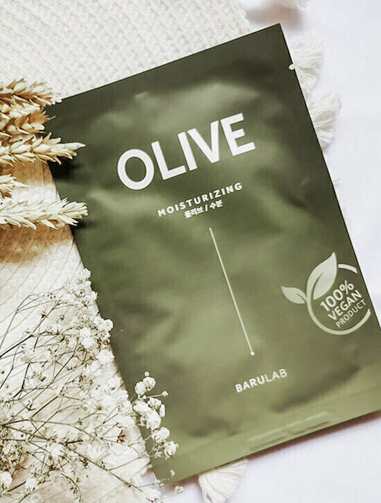 Single Barulab Clean Vegan Olive Mask Sheet package displayed against a natural background with small white flowers and beige wheatgrass.